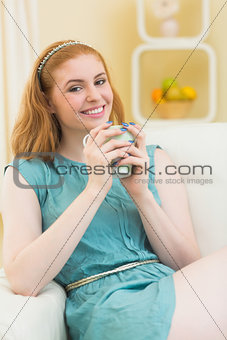 Smiling redhead sitting on the couch and holding mug