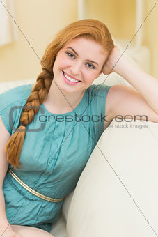 Smiling redhead sitting on the couch looking at camera