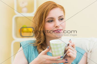 Thinking redhead sitting on the couch having coffee