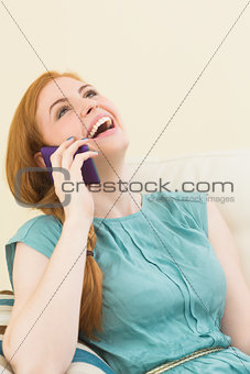 Laughing redhead sitting on the couch making a call