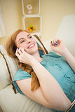 Happy redhead lying on the couch on the phone