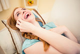 Laughing redhead lying on the couch on the phone