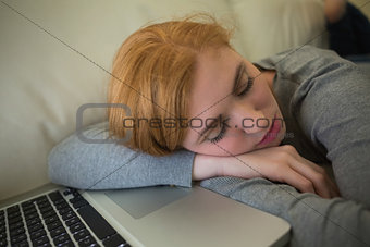 Redhead sleeping on the sofa with her laptop