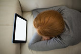 Redhead lying on the sofa watching her tablet pc
