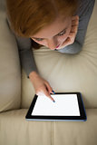 Redhead lying on the couch using her tablet pc