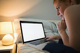 Young redhead lying on her bed using laptop