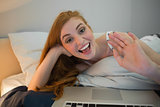Pretty redhead waving to laptop on video chat