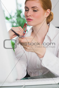 Serious businesswoman working at her desk holding glasses