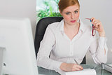Stern businesswoman working at her desk looking at camera