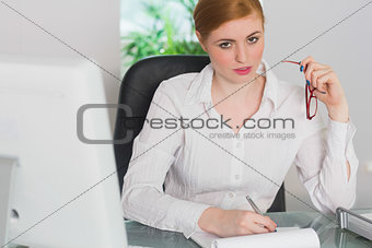 Stern businesswoman working at her desk looking at camera