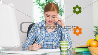 Pretty redhead writing at her desk