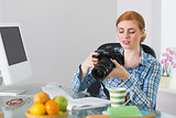 Thoughtful photographer sitting at her desk looking at camera