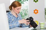 Focused photographer sitting at her desk looking at her camera
