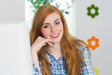Attractive redhead sitting at her desk smiling at camera