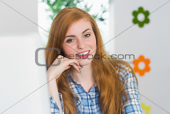 Attractive redhead sitting at her desk smiling at camera