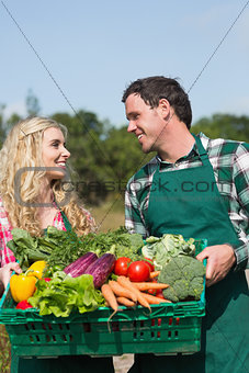Happy couple presenting vegetables while looking at each other