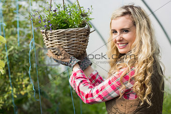 Happy woman touching a hanging flower basket