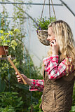 Happy woman holding a clipboard in her green house on the phone