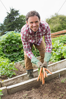 Man wearing a check shirt presenting some carrots