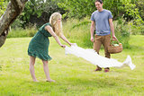 Blonde woman spreading a blanket for a picnic with her boyfriend