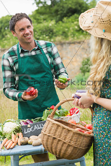 Young handsome farmer selling organic vegetables to pretty blonde
