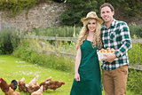 Young couple posing on a lawn holding a basket filled with eggs