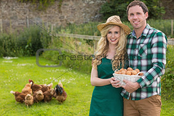 Young couple holding a basket filled with eggs in their garden