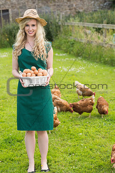 Smiling pretty woman presenting a basket filled with eggs
