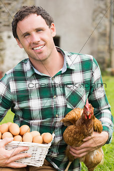 Young man holding his chicken and basket of eggs