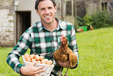 Happy young man holding his chicken and basket of eggs