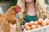 Young couple holding chicken and basket of eggs