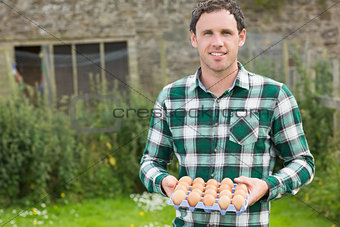 Young smiling man holding carton of eggs