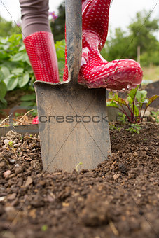 Woman wearing rubber boots using shovel
