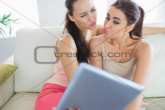 Two pretty young women taking a self portrait with a tablet