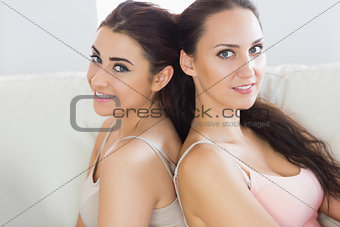 Two cute young women leaning against each other