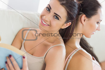 Pretty woman holding a tablet leaning against her friend