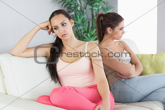 Two annoyed women sitting on a couch