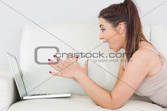 Excited young woman making use of her laptop
