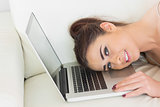 Pretty glad woman lying with her head on a laptop
