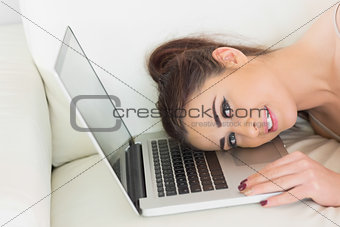 Pretty glad woman lying with her head on a laptop
