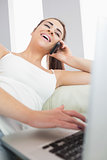 Laughing woman on the phone using laptop