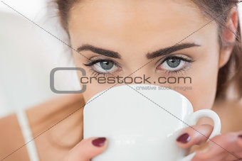 Close up of a cute brunette woman drinking coffee