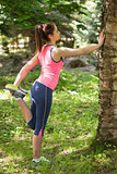 Sporty brunette woman stretching in a forest