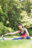 Sporty woman stretching her leg and smiling at camera