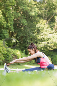 Sporty woman stretching her legs and smiling