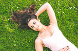 Pretty brunette woman lying on a lawn