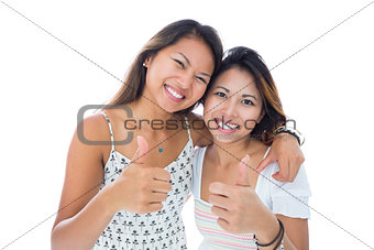 Two smiling asian women giving thumbs up
