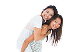 Smiling asian woman giving her sister a piggyback ride