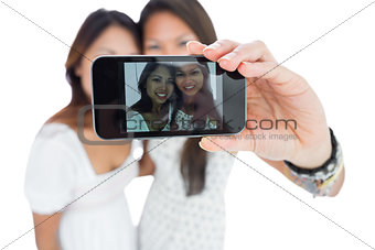 Two smiling asian sisters taking a self portrait