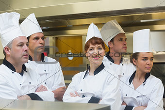 Team of chefs looking away with one smiling at camera
